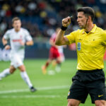 Les 7 meilleures compétences d’arbitre sportif à développer en 2026 Un arbitre sportif observe attentivement une action dynamique sur un terrain de football pendant un match.