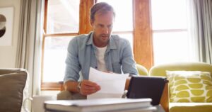 Personne comparant des offres de crédit sans justificatif avec une calculatrice et un carnet de budget sur une table